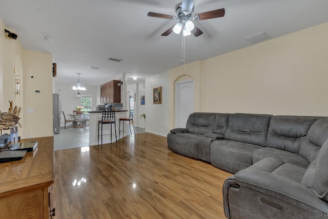 living room featuring light hardwood / wood-style flooring and ceiling fan with notable chandelier