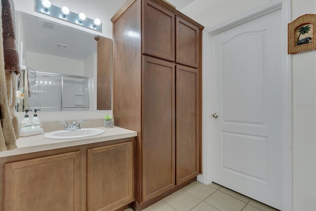 bathroom with vanity, an enclosed shower, and tile patterned floors