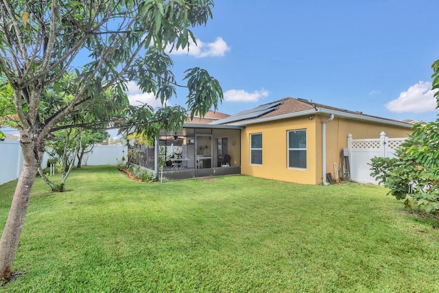 rear view of house featuring a yard, solar panels, and a sunroom