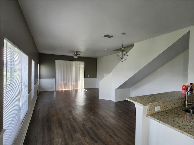 unfurnished living room with ceiling fan with notable chandelier, dark hardwood / wood-style flooring, and sink