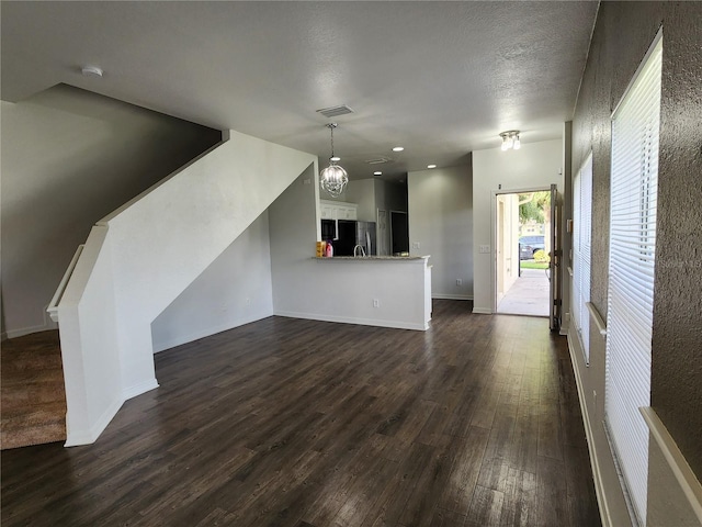 unfurnished living room with dark hardwood / wood-style flooring, an inviting chandelier, and a textured ceiling