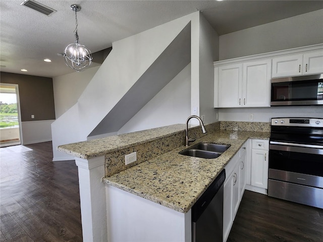 kitchen with light stone countertops, kitchen peninsula, sink, stainless steel appliances, and white cabinetry