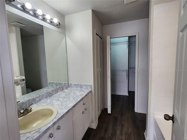 bathroom with a tub, wood-type flooring, a textured ceiling, and vanity