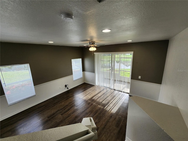 empty room featuring a textured ceiling, ceiling fan, and dark hardwood / wood-style floors