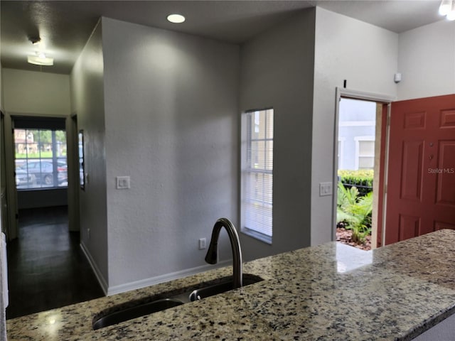 kitchen featuring a wealth of natural light, dark wood-type flooring, sink, and light stone countertops