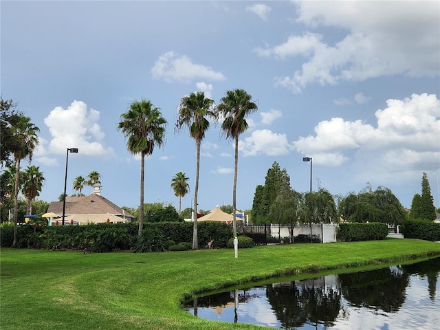 view of property's community with a water view and a lawn