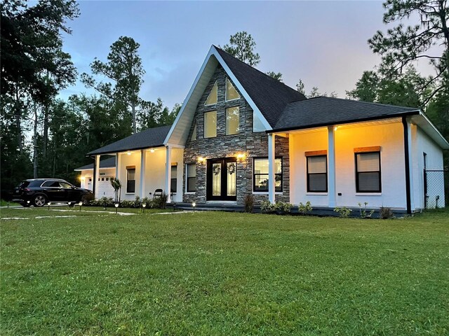 back house at dusk featuring a yard and a porch