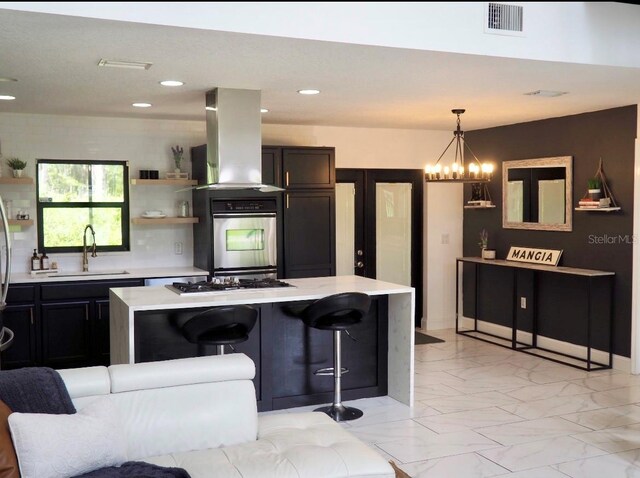 kitchen with a notable chandelier, island exhaust hood, sink, a breakfast bar, and appliances with stainless steel finishes