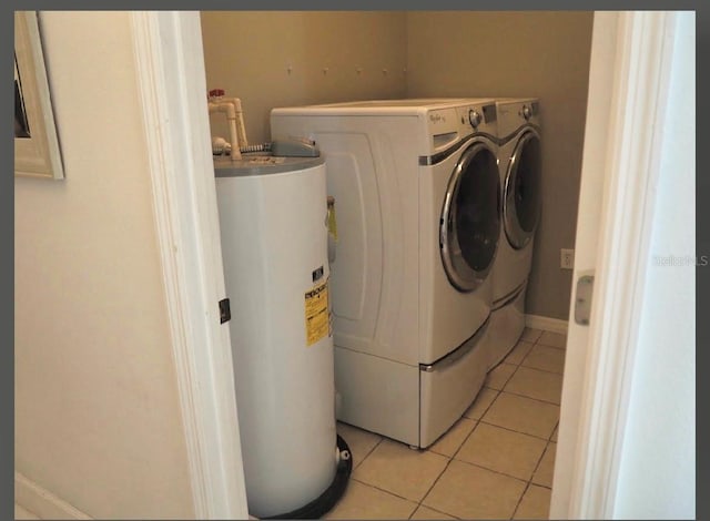 clothes washing area with light tile patterned floors, separate washer and dryer, and water heater