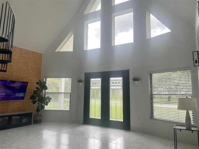 entrance foyer featuring baseboards, marble finish floor, high vaulted ceiling, and a healthy amount of sunlight