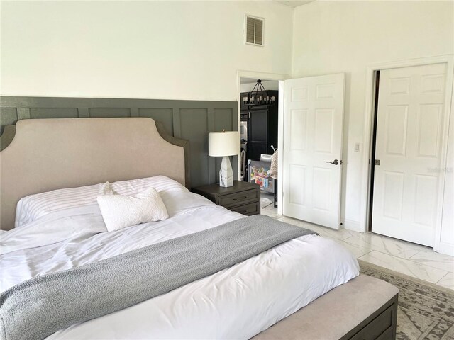 bedroom with marble finish floor, visible vents, a decorative wall, and a wainscoted wall