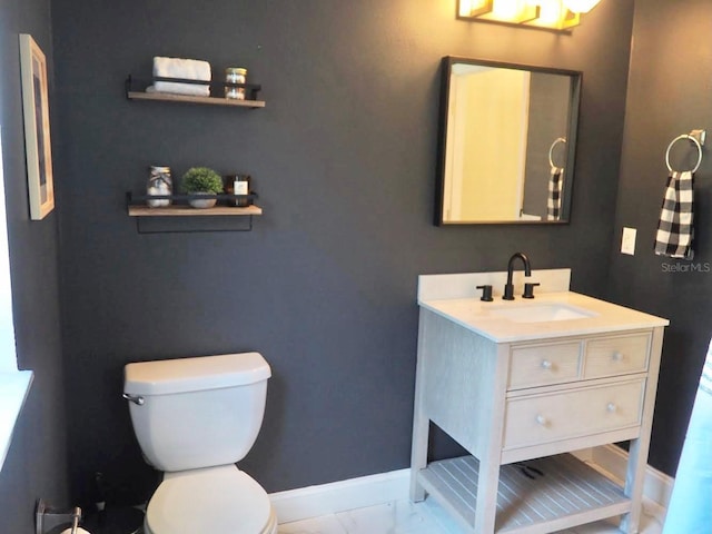 bathroom with marble finish floor, toilet, vanity, and baseboards