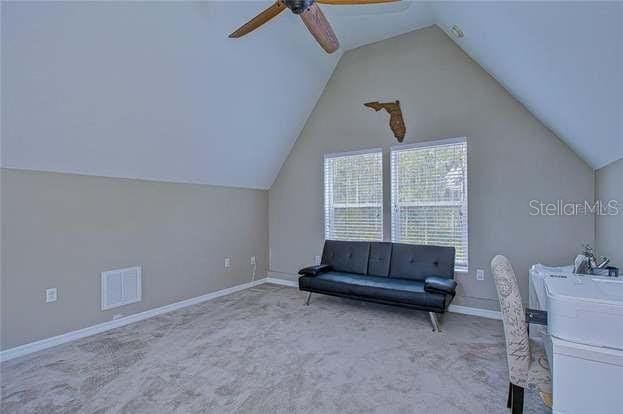 unfurnished office with light carpet, vaulted ceiling, and ceiling fan