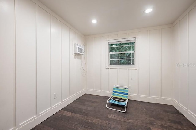 unfurnished room with dark wood-type flooring and an AC wall unit