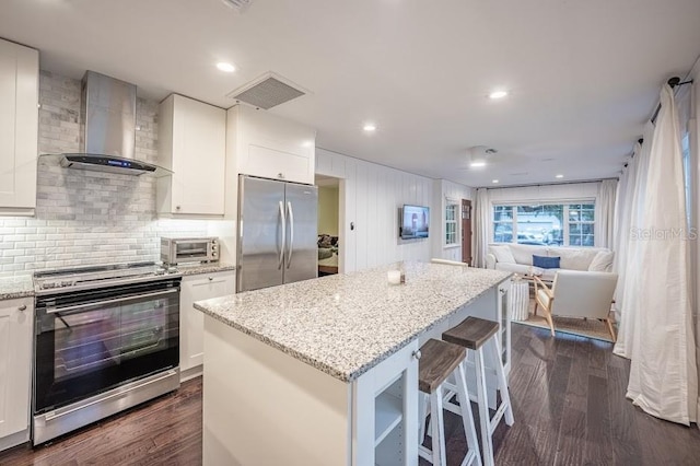 kitchen with dark hardwood / wood-style flooring, stainless steel appliances, wall chimney exhaust hood, and white cabinetry