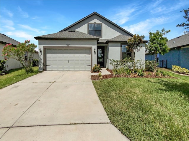 view of front of property with an attached garage, driveway, a front yard, and stucco siding