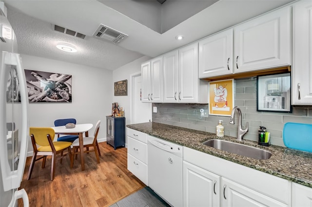 kitchen featuring white cabinets, dark stone counters, sink, and white appliances