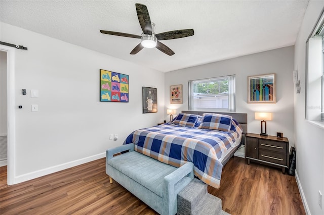 bedroom with dark wood-type flooring, ceiling fan, and a textured ceiling