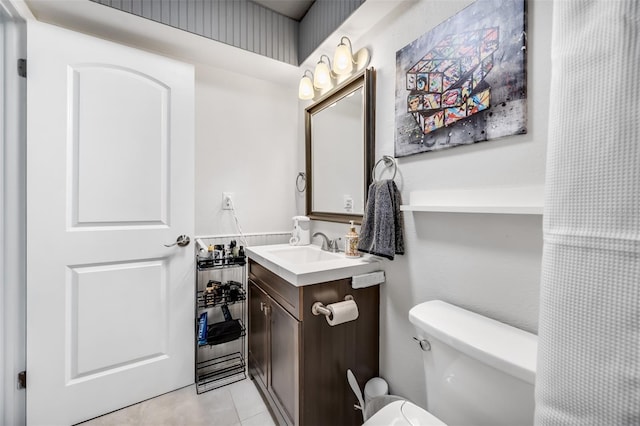 bathroom with toilet, vanity, and tile patterned flooring