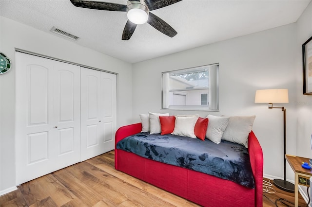 bedroom featuring a textured ceiling, ceiling fan, a closet, and hardwood / wood-style flooring