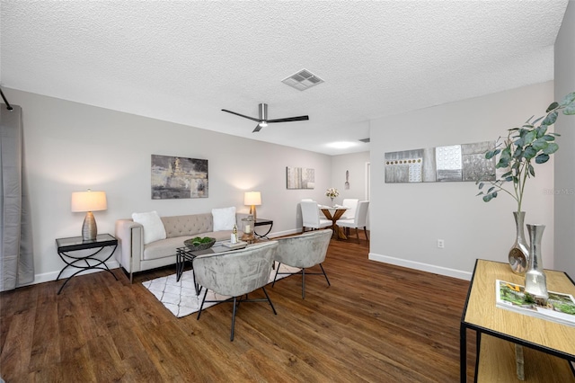 living area featuring visible vents, a ceiling fan, a textured ceiling, wood finished floors, and baseboards