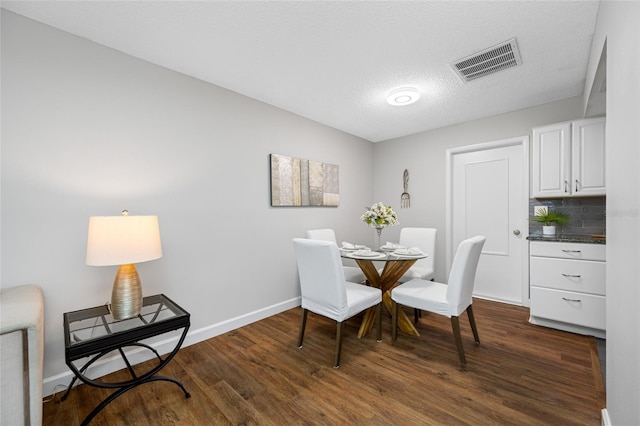 dining area featuring dark wood finished floors, baseboards, visible vents, and a textured ceiling