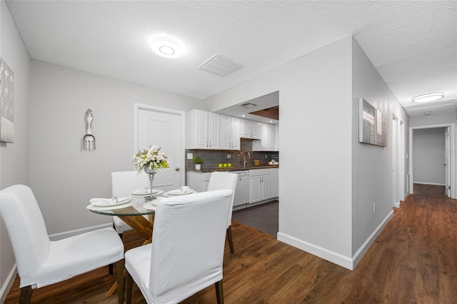 dining space with dark wood finished floors, a textured ceiling, and baseboards