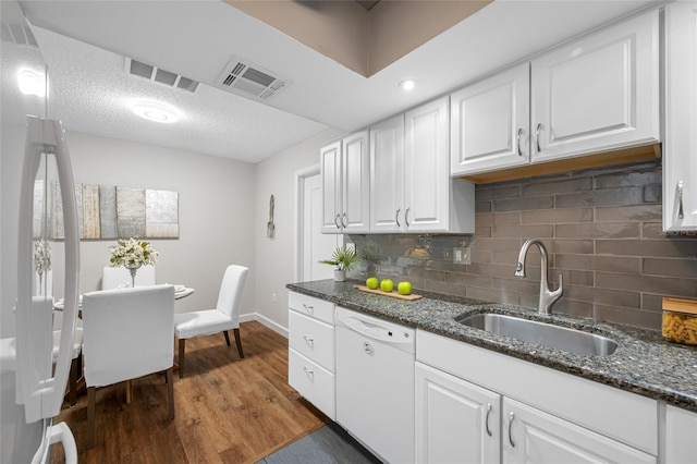 kitchen featuring visible vents, wood finished floors, white cabinetry, white dishwasher, and a sink