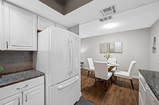 kitchen featuring dark wood-style floors, visible vents, white cabinets, and freestanding refrigerator