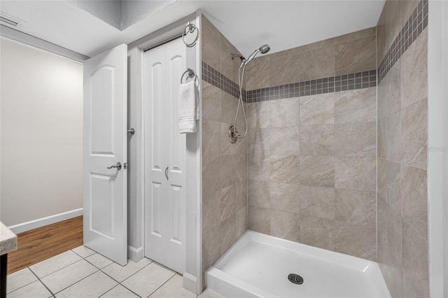 bathroom with tile patterned flooring, visible vents, tiled shower, and baseboards