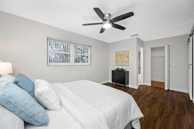 bedroom featuring visible vents, a textured ceiling, a barn door, and wood finished floors