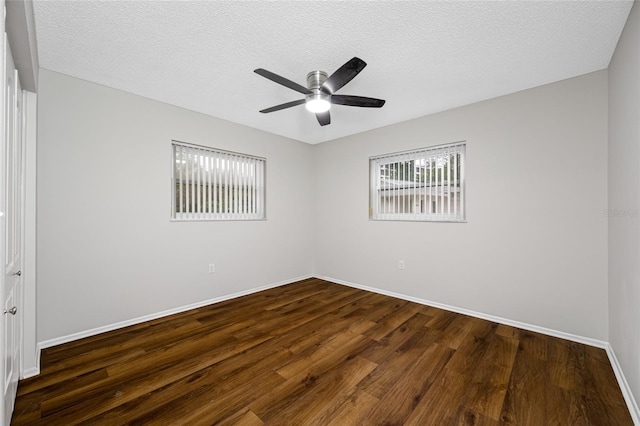 spare room featuring a textured ceiling, dark wood-type flooring, baseboards, and a ceiling fan