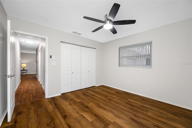 unfurnished bedroom featuring visible vents, baseboards, wood finished floors, a closet, and a textured ceiling