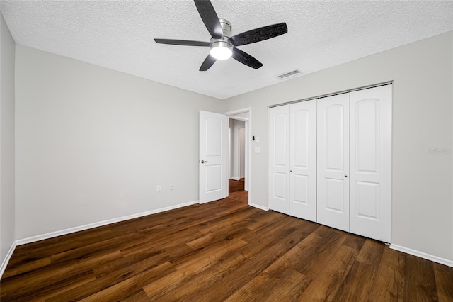 unfurnished bedroom with dark wood finished floors, visible vents, a closet, and a textured ceiling