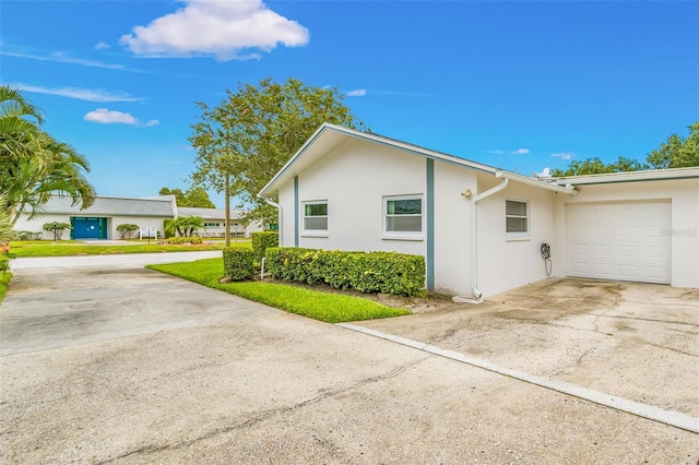 view of side of property featuring stucco siding, concrete driveway, and an attached garage