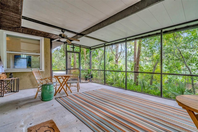 unfurnished sunroom featuring beam ceiling and ceiling fan