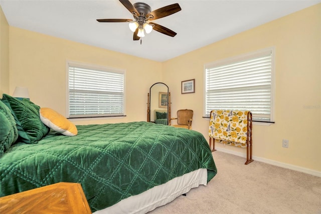 bedroom with multiple windows, ceiling fan, and light carpet