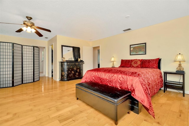 bedroom featuring light wood-type flooring, a textured ceiling, and ceiling fan