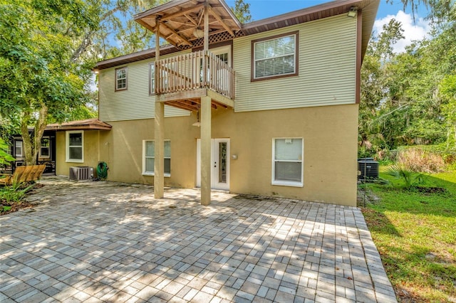 rear view of house with central AC unit, a patio area, and a balcony