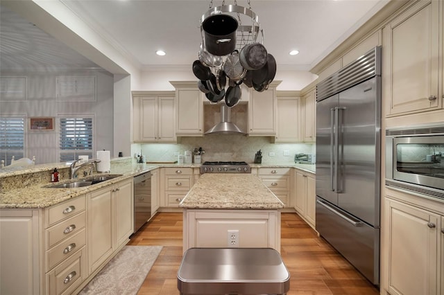825 Islebay Dr, Apollo Beach, FL 33572 - kitchen featuring cream cabinets, a sink, built in appliances, wall chimney range hood, and a peninsula