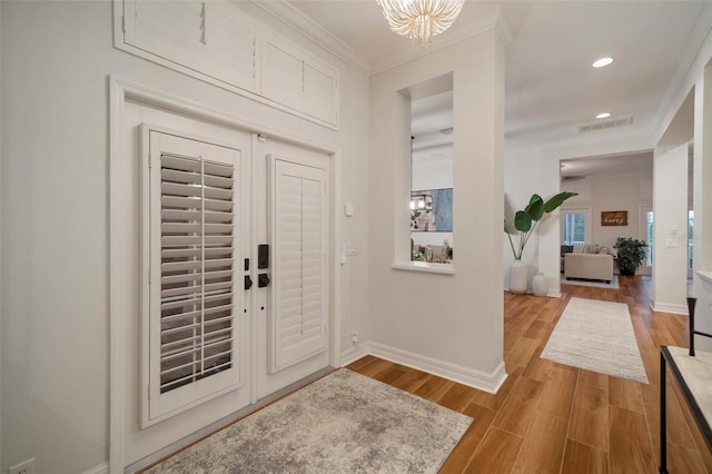 825 Islebay Dr, Apollo Beach, FL 33572 - entrance foyer with visible vents, baseboards, ornamental molding, wood finished floors, and an inviting chandelier