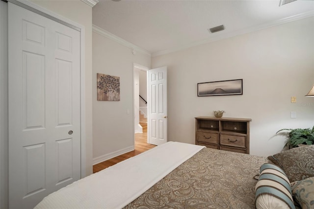 bedroom featuring a closet, light hardwood / wood-style floors, and crown molding