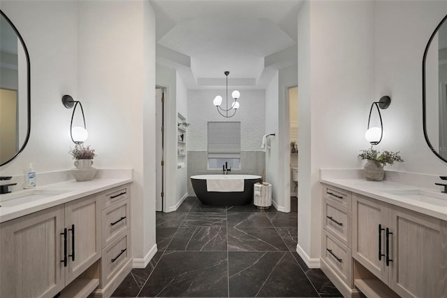 bathroom featuring vanity, a bathing tub, and a chandelier