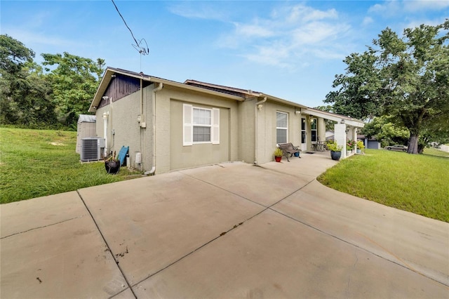 single story home featuring a front lawn, a patio, and central AC unit