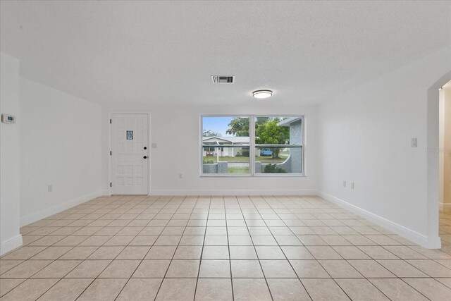 tiled empty room with a textured ceiling