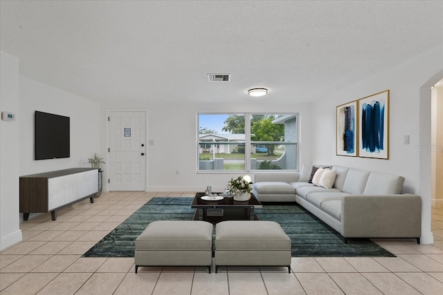 living room with visible vents, a textured ceiling, and light tile patterned floors