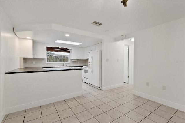 kitchen with white appliances, visible vents, white cabinets, dark countertops, and a peninsula