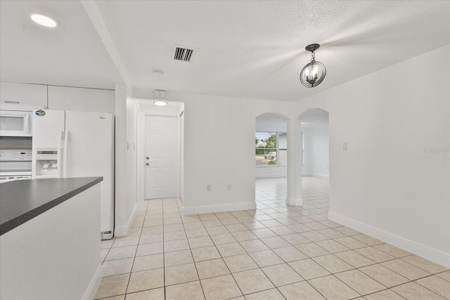 interior space with arched walkways, visible vents, light tile patterned flooring, a textured ceiling, and baseboards