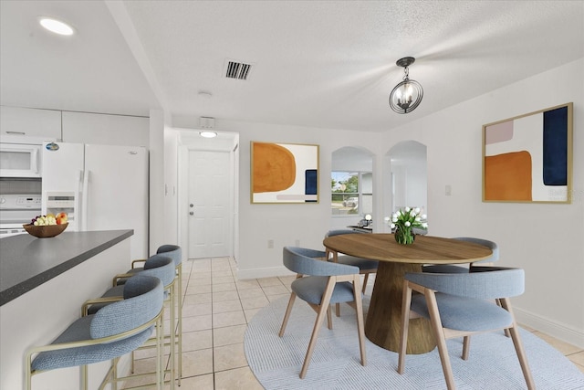 dining room with arched walkways, visible vents, baseboards, and light tile patterned floors