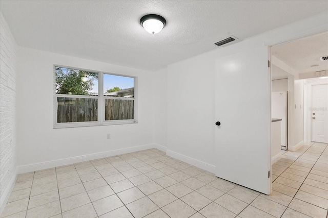 empty room featuring visible vents, a textured ceiling, baseboards, and light tile patterned flooring